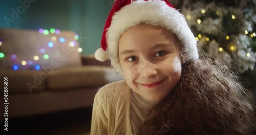 Portrait happy smiling cute child in Christmas hat Santa Clausa. Portrait beautiful happy little girl, child looks in camera. photo