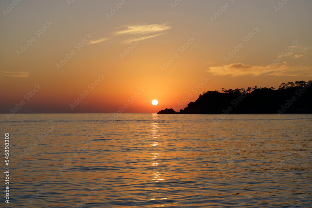 Sunset with tropical mediterranean sea. Evening or morning landscape with beautiful orange sun, calm water and soft light in summer