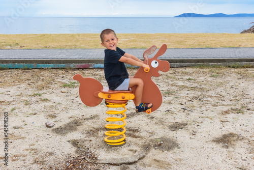 A boy rides a donkey on a children's playground
