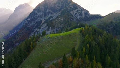 Aerial view orbiting Austrian forested alpine hillside as surays shine through Tyrol mountain landscape photo