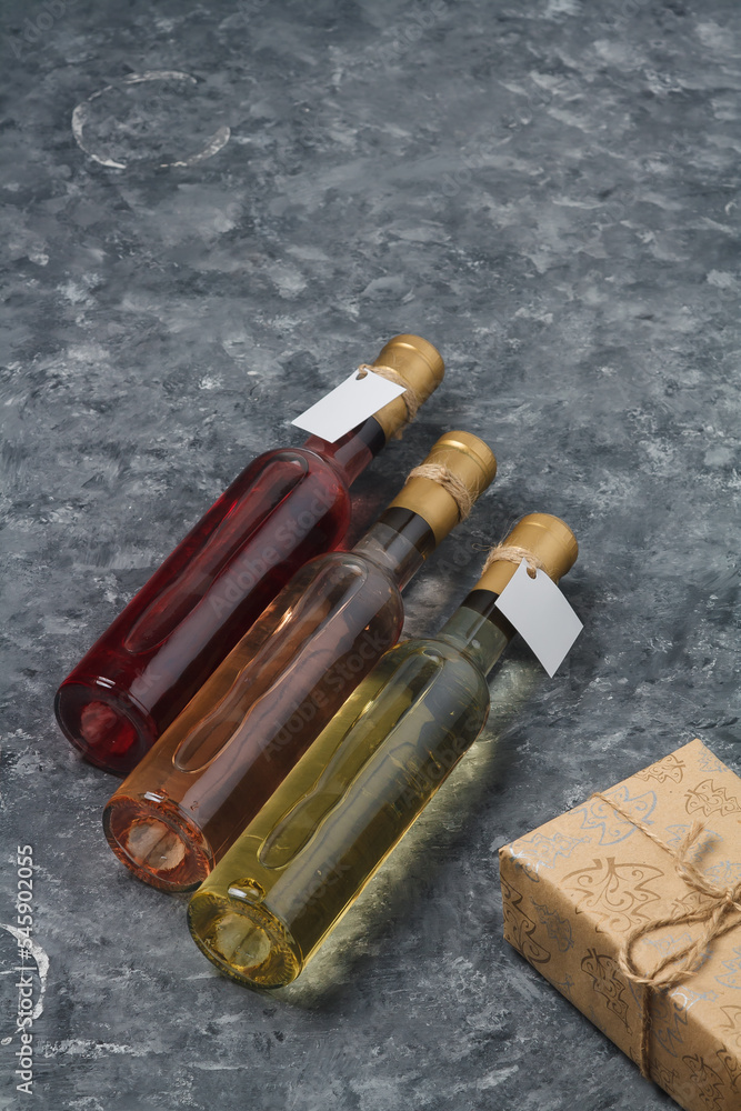 Christmas wine and present box. Three bottles of red and white wine, no brand, mock up on grey background. Copy space, vertical shot Christmas wine and present box. Three bottles of red and white wine, no brand, mock up on grey background. Copy space, vertical shot