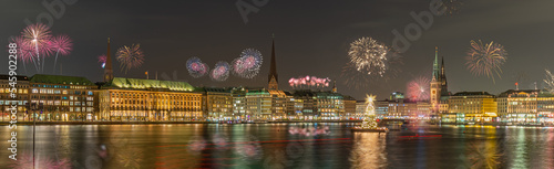 Panorama view of citycenter from Alster Lake,view to Hamburg Rathaus and fountain in the center of the lake with fireworks. Festive atmosphere with fireworks in Hamburg. Silvester in Hamburg. photo