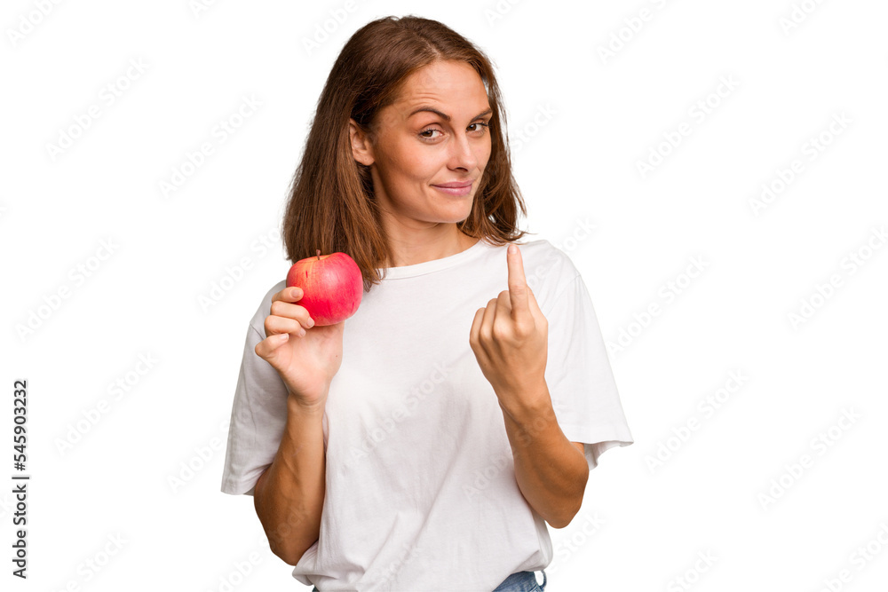 Young caucasian woman holding a red apple isolated pointing with finger at you as if inviting come closer. Young caucasian woman holding a red apple isolated pointing with finger at you as if inviting come closer.