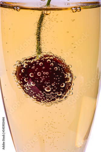 Cherry in a champagne glass, covered with gas bubbles, macro photography
