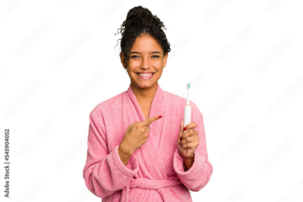Young brazilian woman holding an electric toothbrush isolated smiling and pointing aside, showing something at blank space. Young brazilian woman holding an electric toothbrush isolated smiling and pointing aside, showing something at blank space.