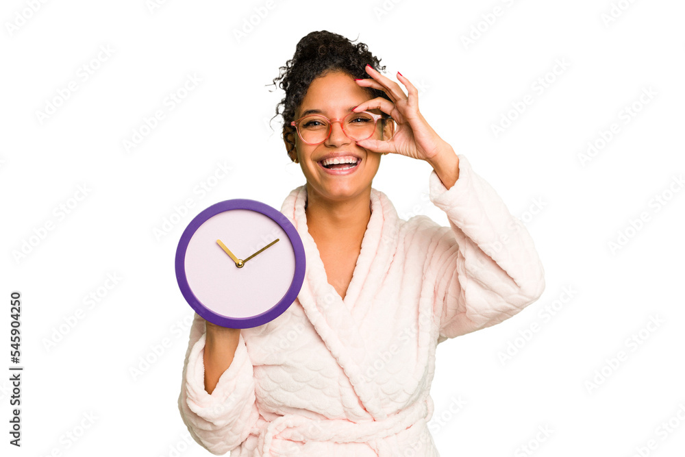 Young brazilian woman wearing a pajama holding a clock isolated excited keeping ok gesture on eye. Young brazilian woman wearing a pajama holding a clock isolated excited keeping ok gesture on eye.