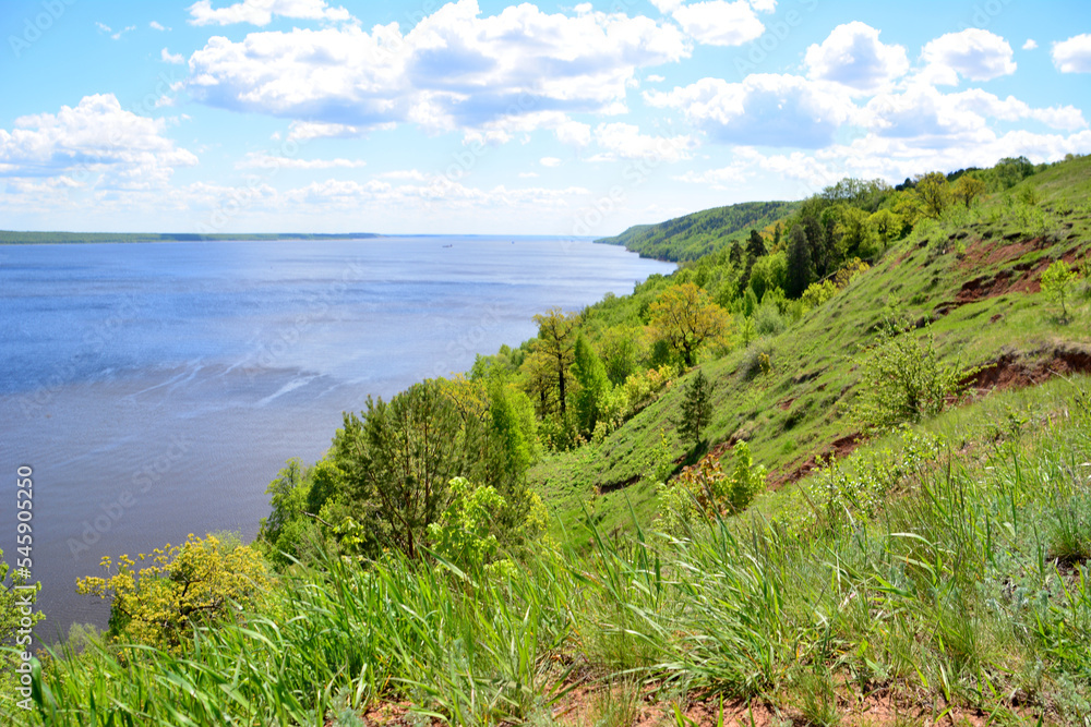 green rolling hills with volga river and blue sky with clouds on background