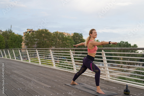 lateral view of Girl realizing yoga in the middle of the city, warrior pose