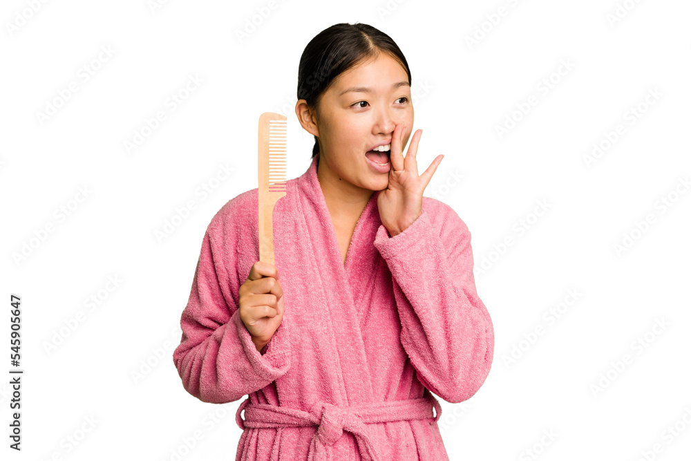 Young asian woman holding an hair comb isolated shouting and holding palm near opened mouth. Young asian woman holding an hair comb isolated shouting and holding palm near opened mouth.
