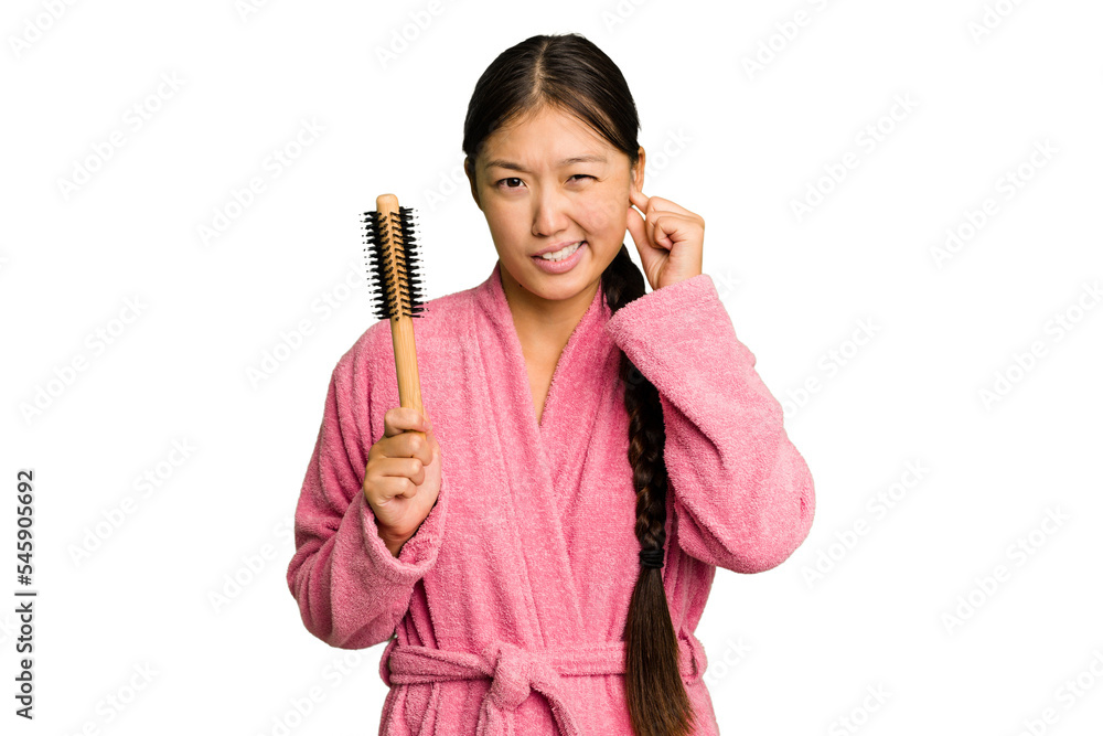 Young asian woman holding an hair comb isolated covering ears with hands. Young asian woman holding an hair comb isolated covering ears with hands.