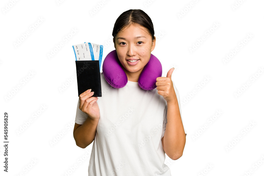 Young asian woman with inflatable travel pillow on her neck holding passport isolated smiling and raising thumb up