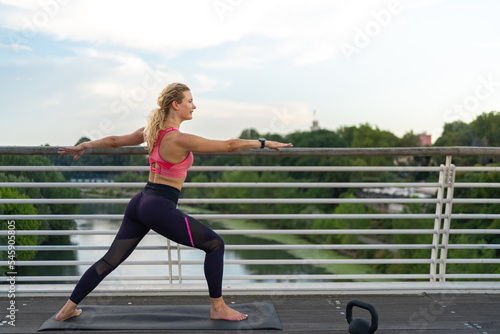 lateral view of Girl realizing yoga in the middle of the city, warrior pose