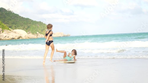 A child rides a skimboard on the coast of an island in the tropics photo