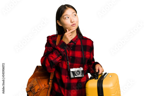 Traveler asian woman holding a suitcase isolated looking sideways with doubtful and skeptical expression.