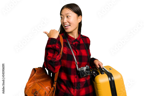Traveler asian woman holding a suitcase isolated points with thumb finger away, laughing and carefree.
