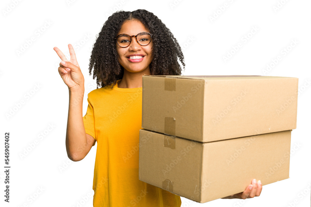 Young african american woman moving to other house while picking up a box full of things isolated joyful and carefree showing a peace symbol with fingers. Young african american woman moving to other house while picking up a box full of things isolated joyful and carefree showing a peace symbol with fingers.