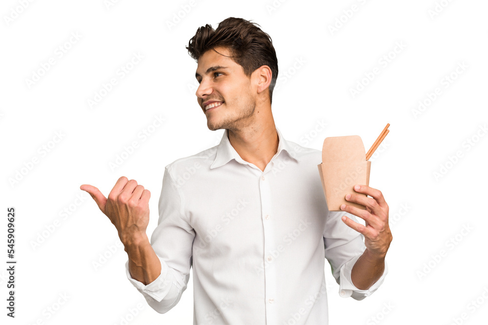 Young caucasian man holding a takeaway of noodles isolated points with thumb finger away, laughing and carefree. Young caucasian man holding a takeaway of noodles isolated points with thumb finger away, laughing and carefree.