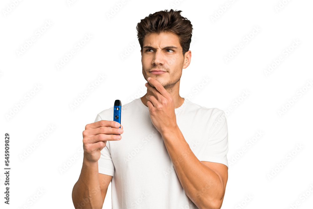 Young caucasian man holding an electronic cigarette isolated looking sideways with doubtful and skeptical expression. Young caucasian man holding an electronic cigarette isolated looking sideways with doubtful and skeptical expression.