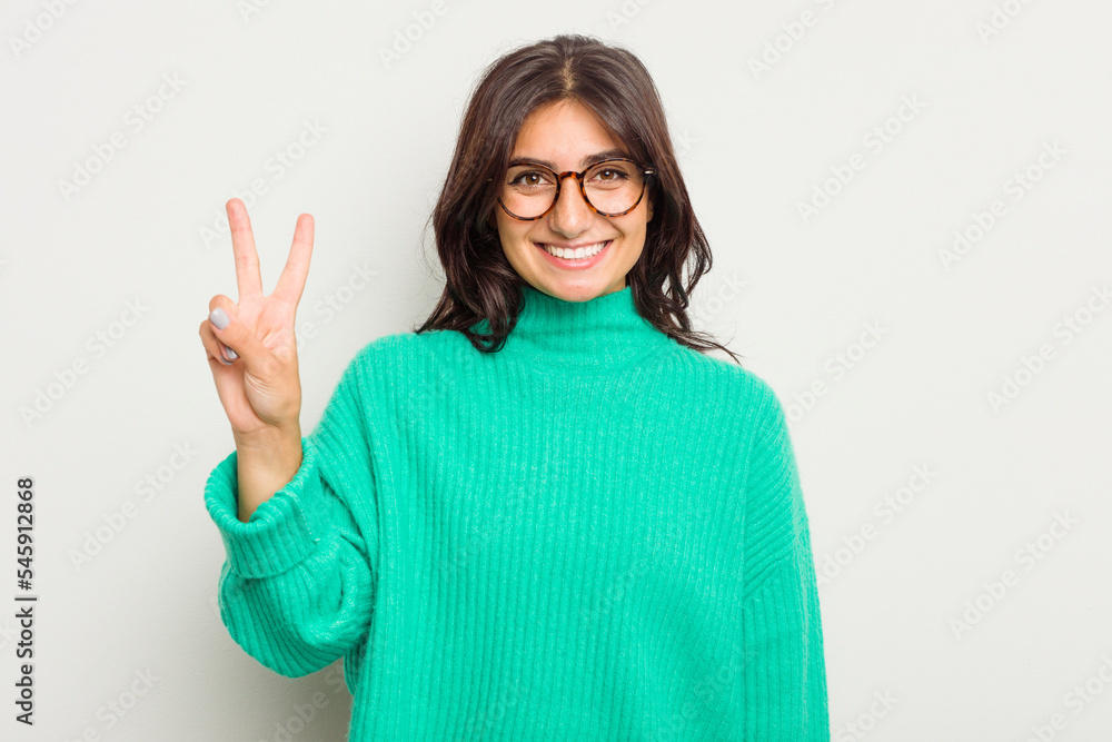 Young Indian woman isolated on white background joyful and carefree showing a peace symbol with fingers. Young Indian woman isolated on white background joyful and carefree showing a peace symbol with fingers.