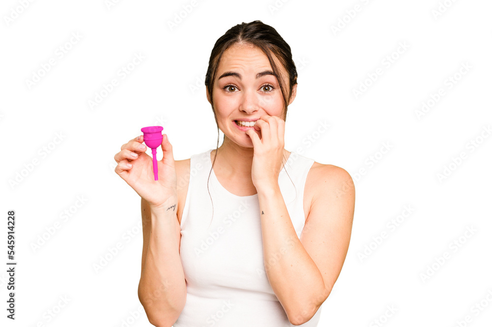 Young caucasian woman holding menstrual cup isolated on green chroma background biting fingernails, nervous and very anxious. Young caucasian woman holding menstrual cup isolated on green chroma background biting fingernails, nervous and very anxious.