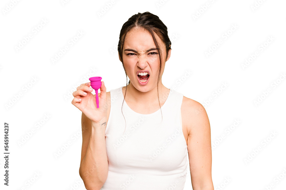 Young caucasian woman holding menstrual cup isolated on green chroma background screaming very angry and aggressive. Young caucasian woman holding menstrual cup isolated on green chroma background screaming very angry and aggressive.
