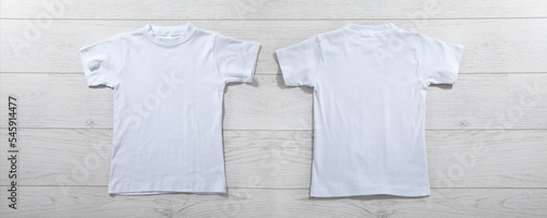 Front and back views on boys t-shirts on white wooden desk background. Mockup for design closeup