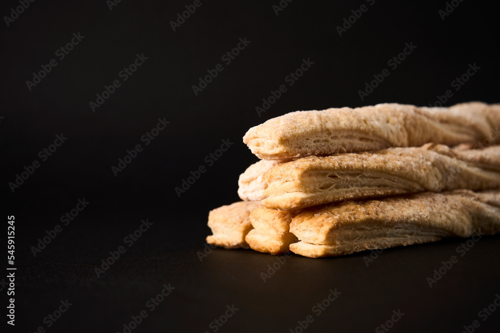 Puff pastry sticks with cinnamon on black background Puff pastry sticks with cinnamon on black background