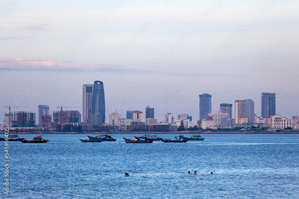 Fototapeta premium People swimming at Nguyen Trai Beach in Da Nang at dusk.