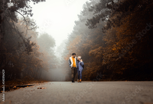 Couple spending time together walking on forest road on a foggy morning.