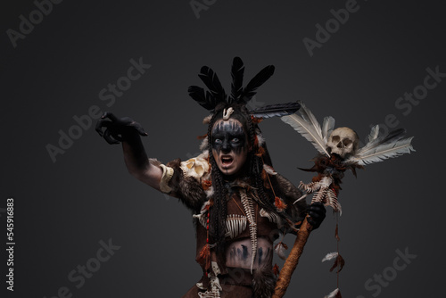Shot of screaming dark wizard dressed in aboriginal attire against grey background.