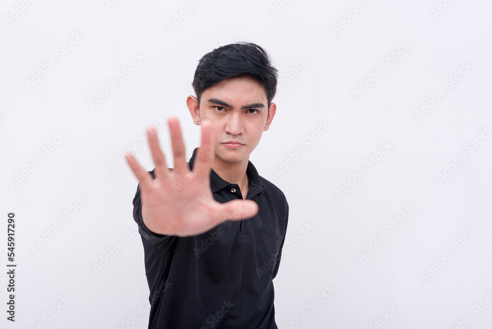 A stern young man commands to stop. Rejecting an offer or deal. Mad or irked from a proposal. Isolated on a white background. A stern young man commands to stop. Rejecting an offer or deal. Mad or irked from a proposal. Isolated on a white background.