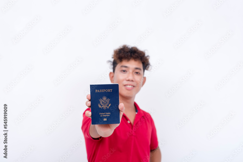 A happy asian guy shows his newly acquired US passport. A naturalized american citizen. Isolated on a white background. A happy asian guy shows his newly acquired US passport. A naturalized american citizen. Isolated on a white background.