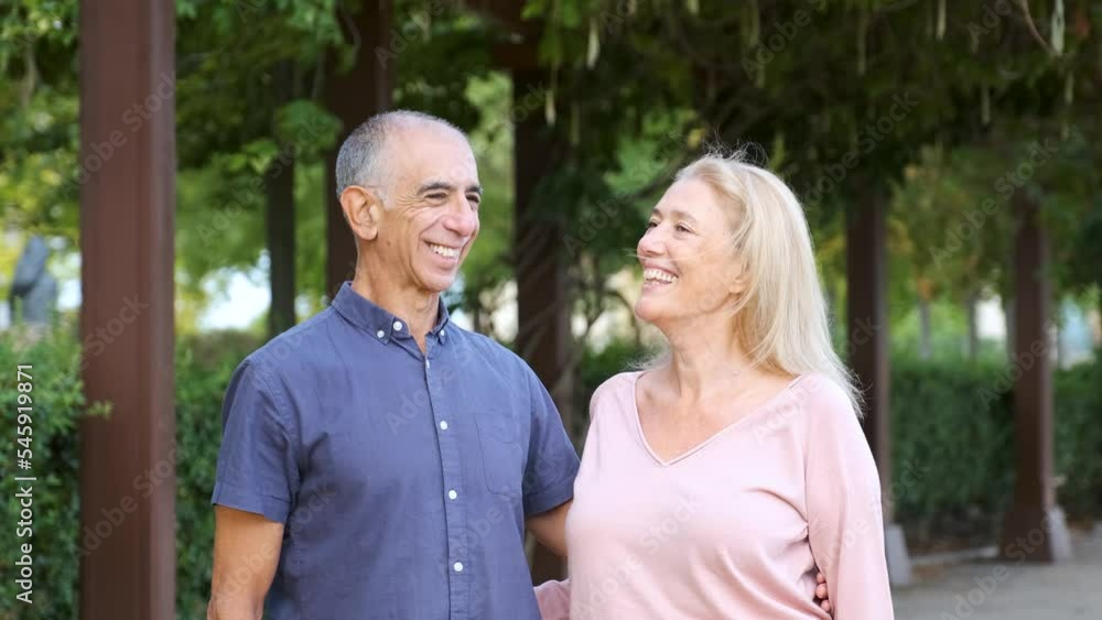 Happy mature couple looking each other, looking at camera and smile in a park at street. Happy mature couple looking each other, looking at camera and smile in a park at street.