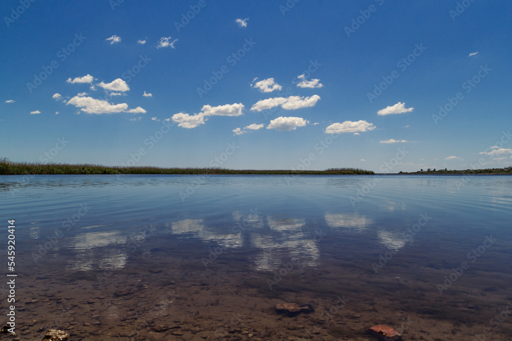 Clouds reflection in lake landscape photo. Beautiful nature scenery photography with lakeshore on background. Idyllic scene. High quality picture for wallpaper, travel blog, magazine, article