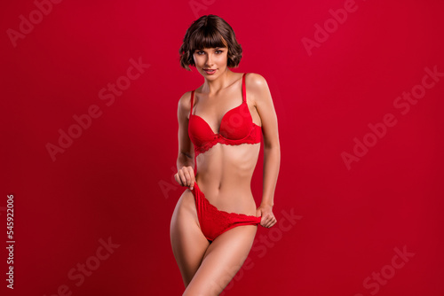 Portrait of attractive kinky chic slim naked girl posing wearing new collection isolated over bright red color background