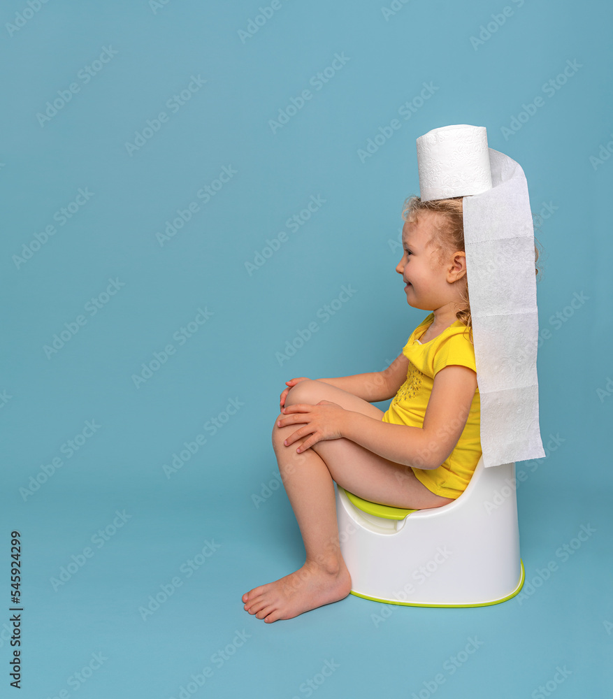 A child on the potty plays with toilet paper. Toilet training. Stock
