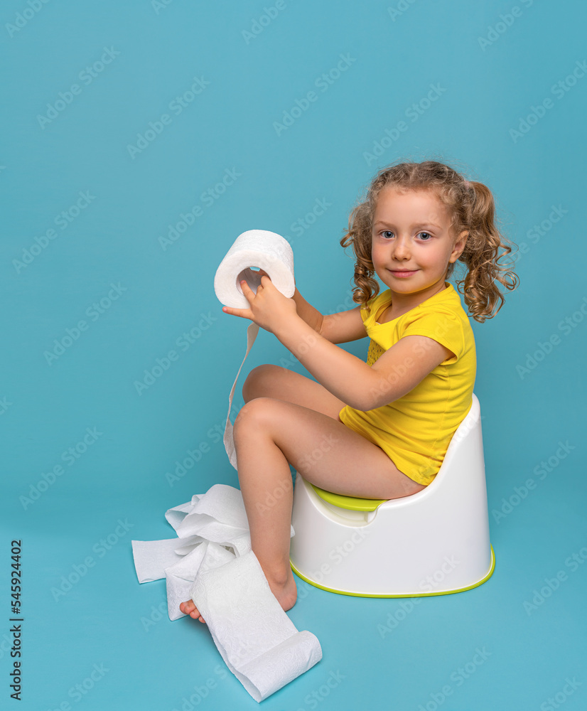 A child on the potty plays with toilet paper. Toilet training. Stock