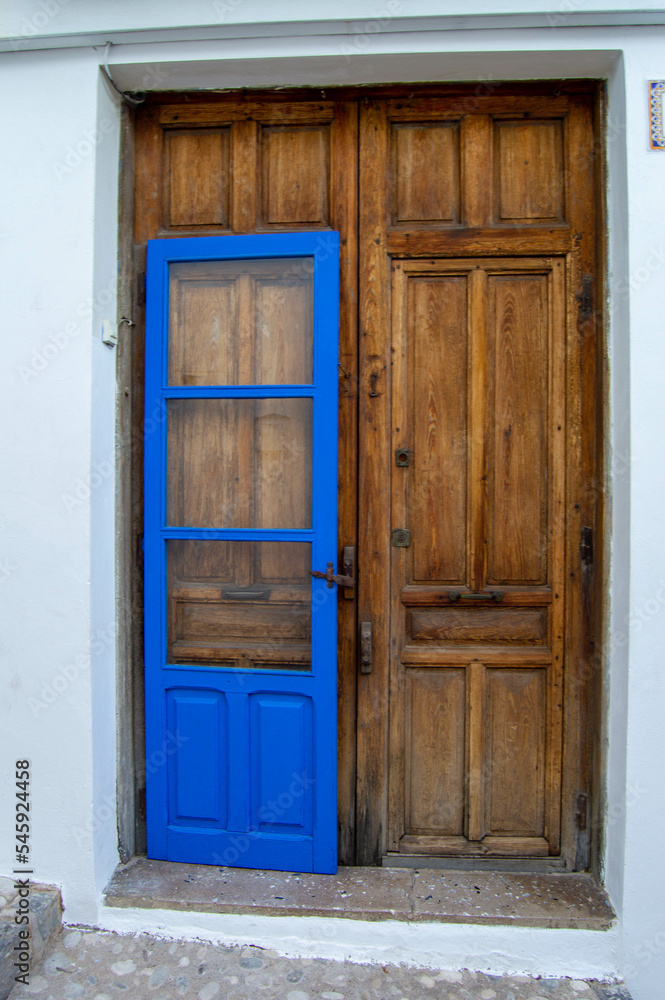 Gran puerta de madera marrón de una casa del pequeño pueblo de Altea en Alicante con otra puerta más pequeña delante pintada de azul.