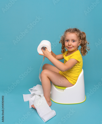 Fotografia A child on the potty plays with toilet paper. Toilet training.