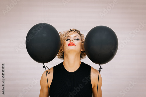 Portrait beautiful woman of model appearance with dark balloons. Art shooting from unusual angles. High quality photo