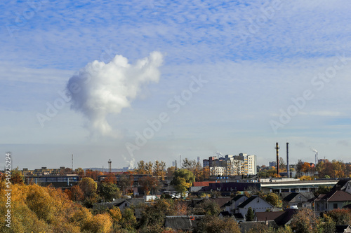 intense cloud of smoke from the plant's pipes against the blue sky, environmental pollution