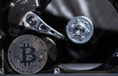Silver Bitcoin coin on background the opened HDD disk. Electronic money, cryptocurrency