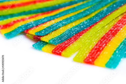 rainbow sour jelly candies strips in sugar sprinkle on white background