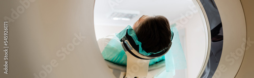 Photography adult brunette man doing diagnostics on computed tomography scanner in clinic, banner