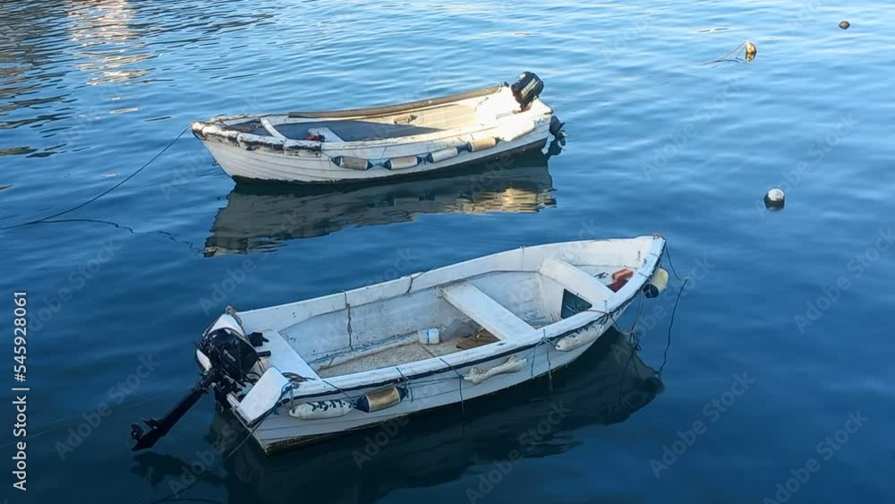Two small fishing boats moored at the maritime pier, with calm and blue waters Two small fishing boats moored at the maritime pier, with calm and blue waters