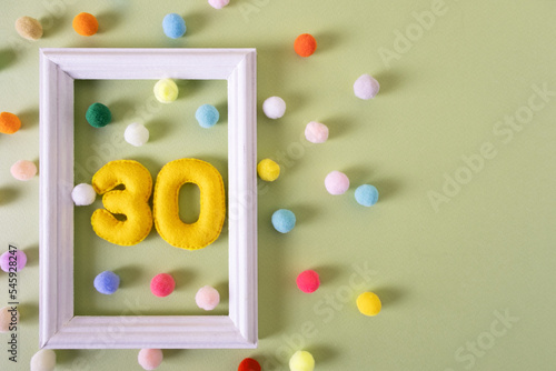 The number Thirty for a birthday in a white frame with colored balls. Festive concert, party, anniversary