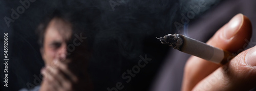 Passive smoking concept. Man is smoking cigarette and man is covering her face. A lot of smoke around.