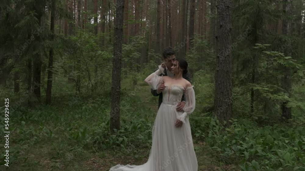 The newlyweds hug against the backdrop of coniferous trees. The newlyweds hug against the backdrop of coniferous trees.