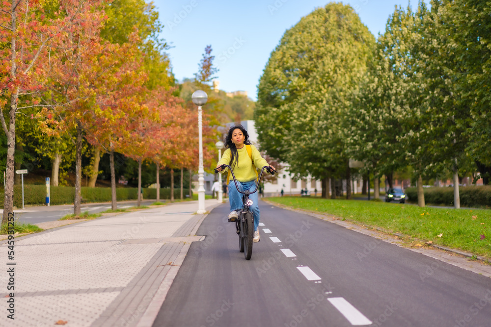 Young Asian female student riding a bicycle on her way to university along the bike lane, healthy living, eco-friendly Young Asian female student riding a bicycle on her way to university along the bike lane, healthy living, eco-friendly