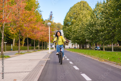 Young Asian female student riding a bicycle on her way to university along the bike lane, healthy living, eco-friendly